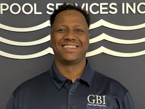 Person smiling in a navy GBI Pool Services Inc. shirt in front of the company logo wall.