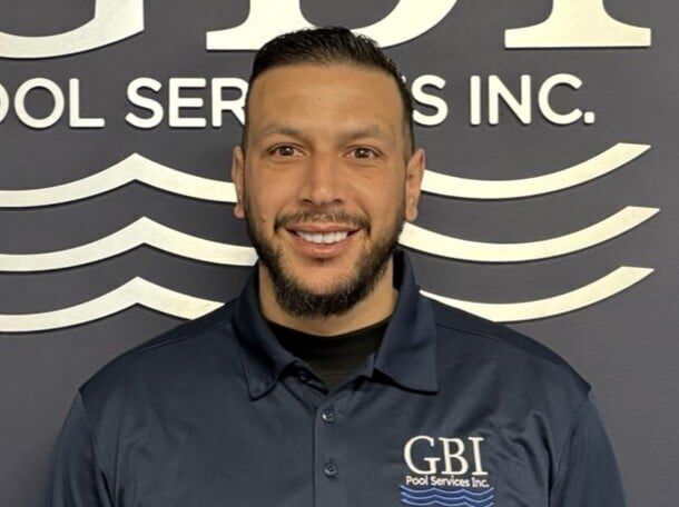 Smiling man in navy GBI Pool Services Inc. shirt, representing Ottawa pool cleaning technicians.